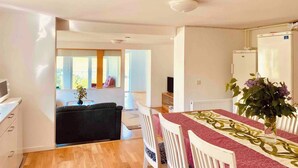 Une cuisine moderne avec des meubles blancs, un coin repas avec une table dressée pour quatre personnes, et une vue sur le balcon.