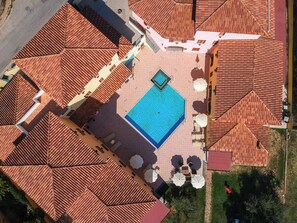 An aerial view of a courtyard with a swimming pool, tiled roofs, and outdoor seating.