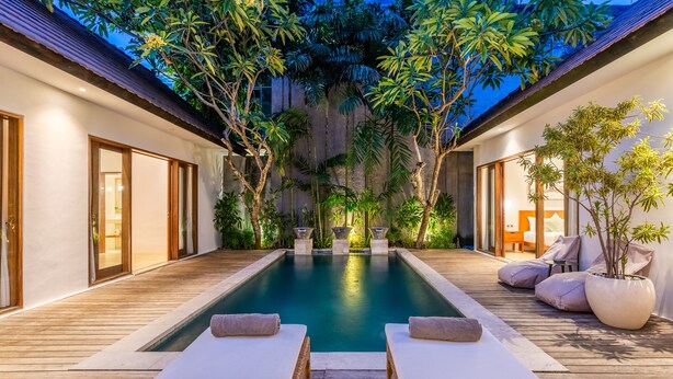 A pool area with two lounge chairs, wooden deck, and surrounding greenery. - Top Choice 3 Bedrooms Pool Villa in Central Canggu (Canggu)