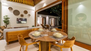 A modern dining area with a round wooden table set for six, surrounded by wooden chairs. - Top Choice 3 Bedrooms Pool Villa in Central Canggu (Canggu)