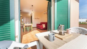 An open-plan living area with a dining table, a red sofa, and a kitchen visible through the open space.