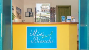 A reception desk with a sign reading "Miti Bianchi" and various informational posters and keychains.