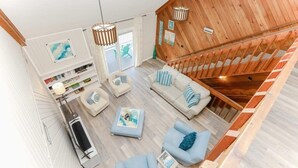 Uma sala de estar ampla com escada de madeira, um conjunto de sofás e uma mesa de centro.