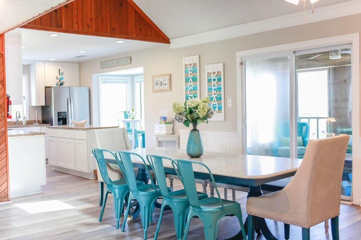 Een moderne keuken met witte kasten, een roestvrijstalen koelkast en een eethoek met een tafel en stoelen.