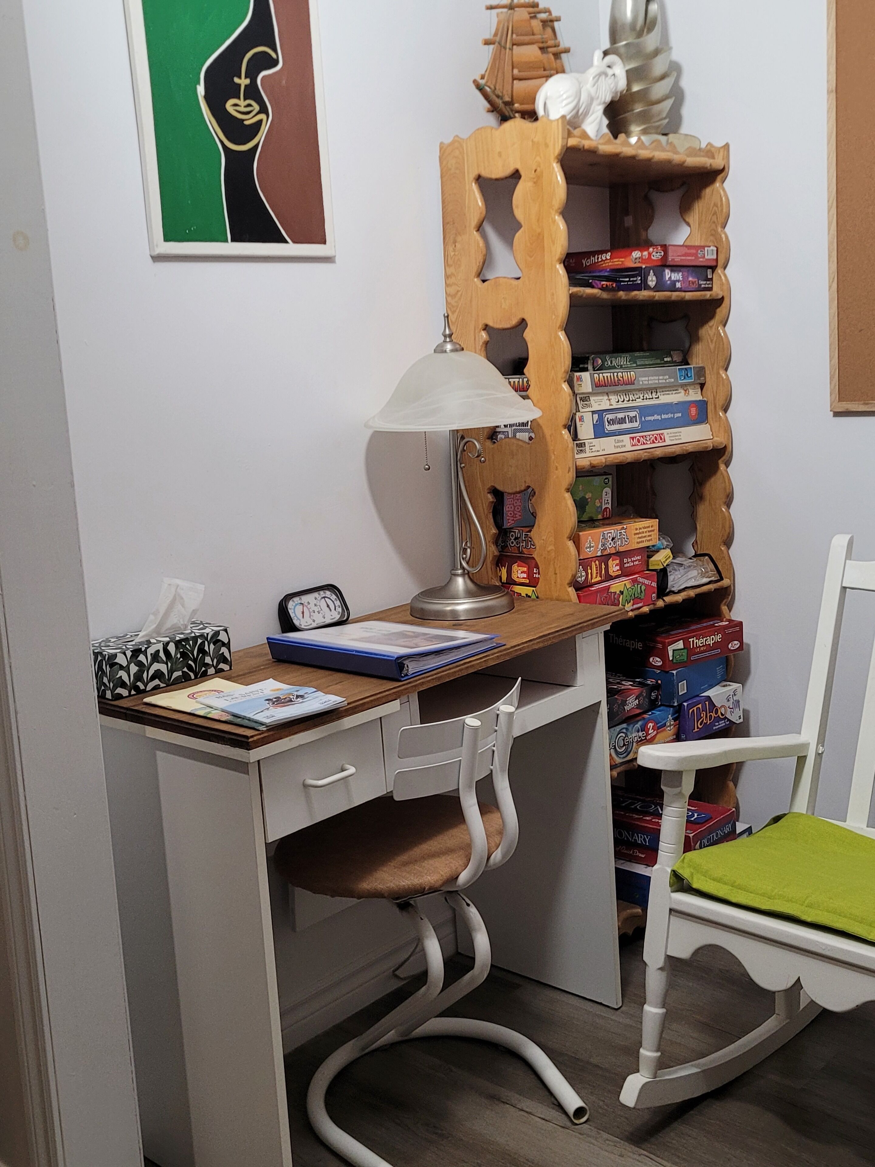 Een bureau met een lamp, een stoel en planken met gezelschapsspellen.