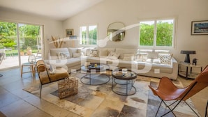 Ein geräumiges Wohnzimmer mit einer großen Couch, zwei Couchtischen und einem Essbereich mit Stühlen.