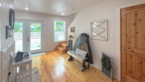 A room with wooden flooring, a bench with a metal frame, a door, and a window. - Downtown Historic Loop Downstairs King Free Parking (Eureka Springs)