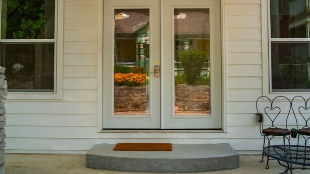 A house with a front door, two windows, a stone pillar, and a small outdoor seating area. - Downtown Historic Loop Downstairs King Free Parking (Eureka Springs)