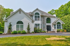 A two-story house with a stone facade, large windows, and a well-maintained lawn.