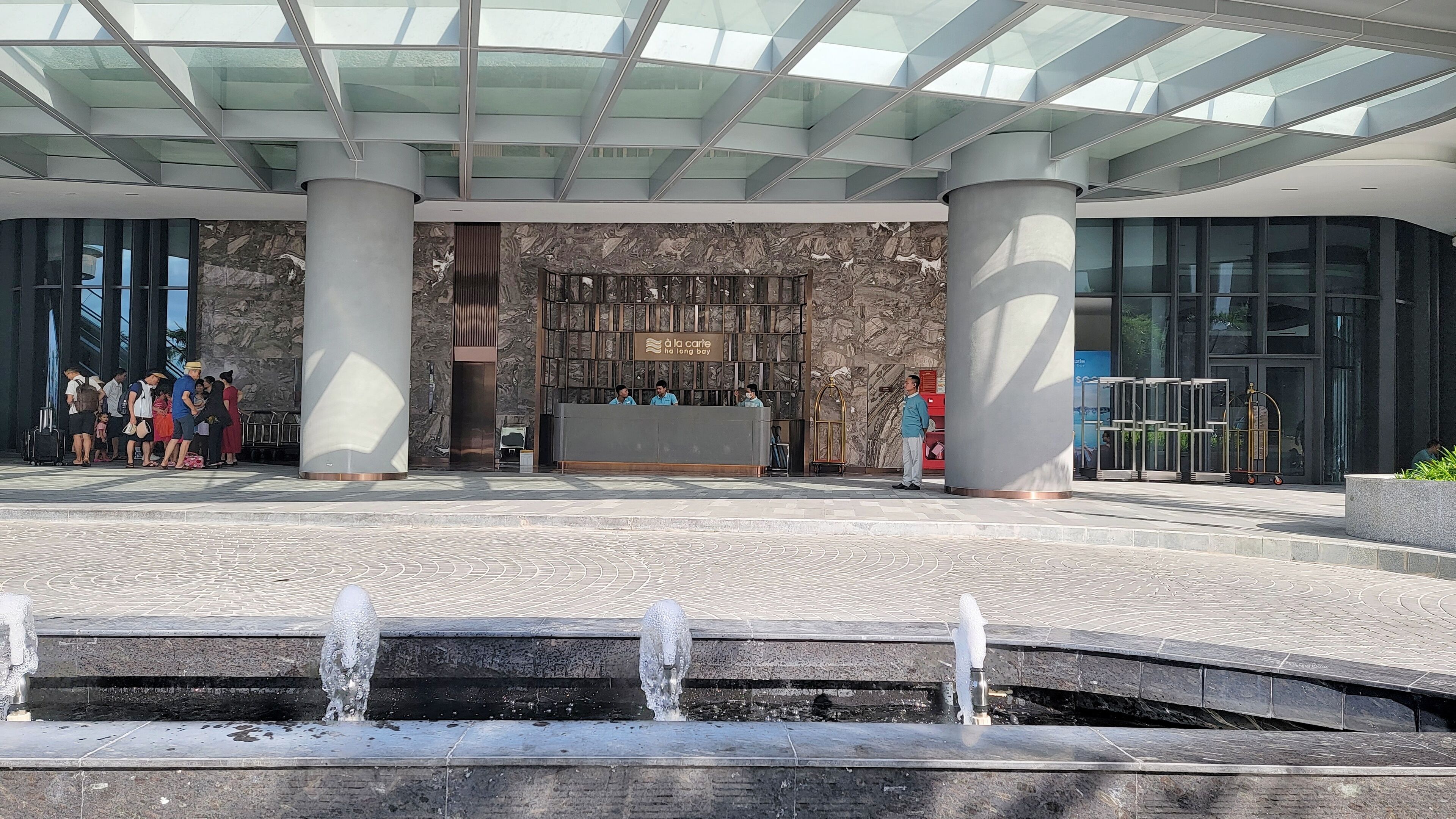 Ein Hotel Eingangsbereich mit einer Rezeption, einer Marmorwand und einer Glasdecke.