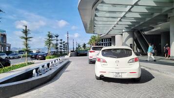Un edificio moderno con fachada de vidrio y un área de estacionamiento con varios automóviles.