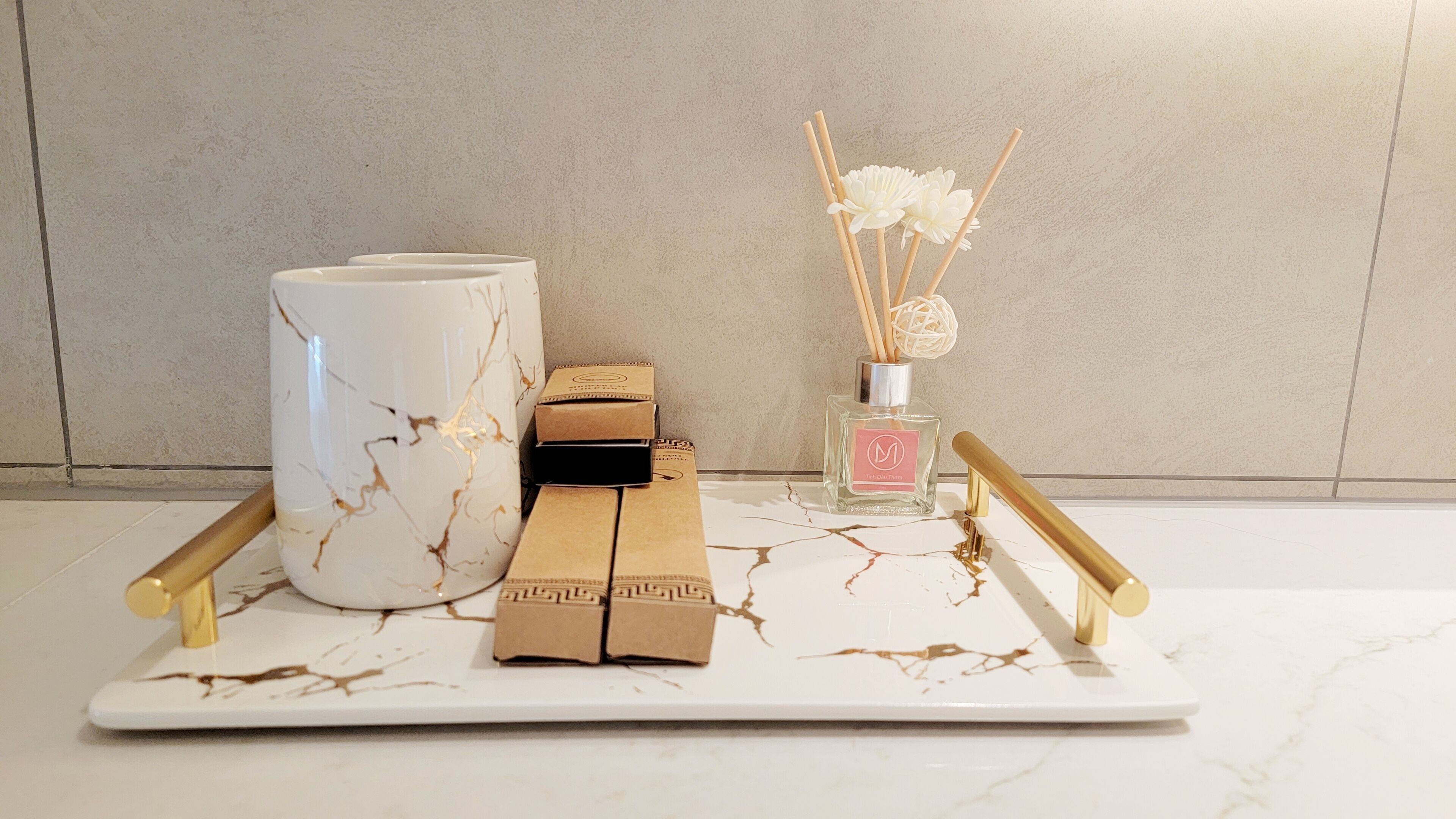 A marble-tiled table with a white vase, a perfume bottle, and a decorative item.