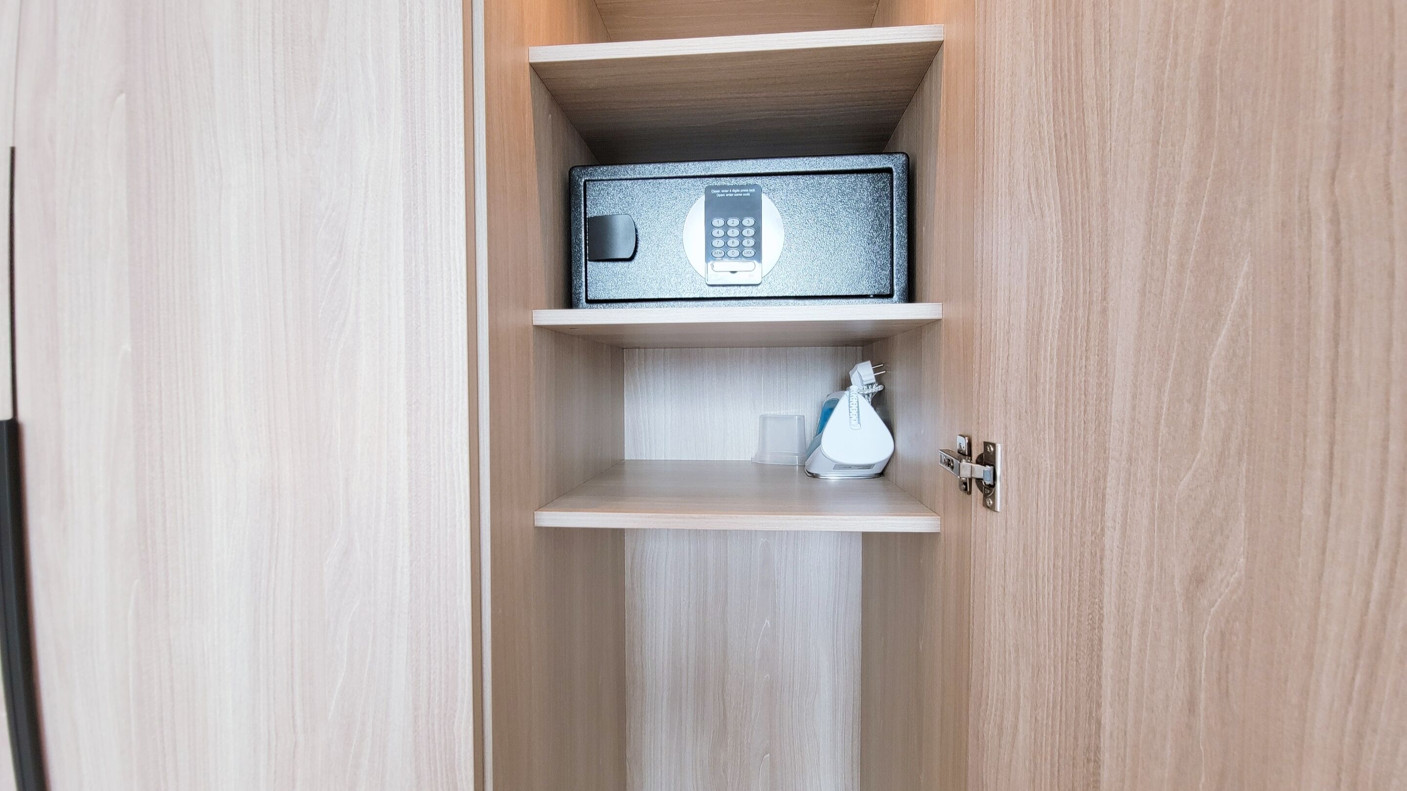 A wooden cabinet with a safe containing a keypad lock.