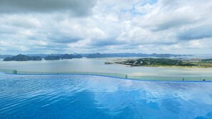 Una piscina con vista a un paisaje costero, que incluye islas y una ciudad distante.