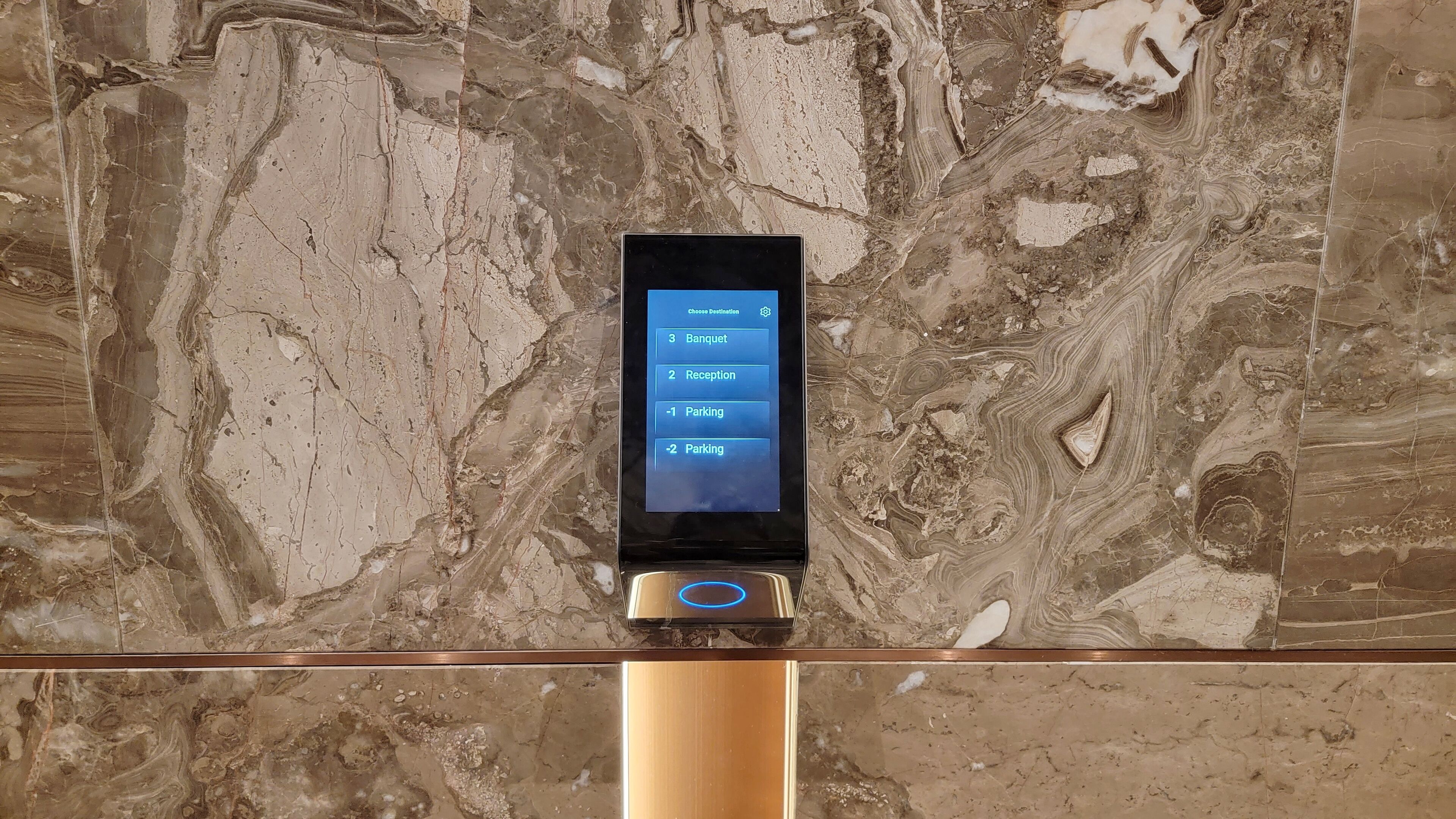 A digital kiosk with a screen displaying options for 'Banquet,' 'Reception,' and 'Parking' on a marble wall.