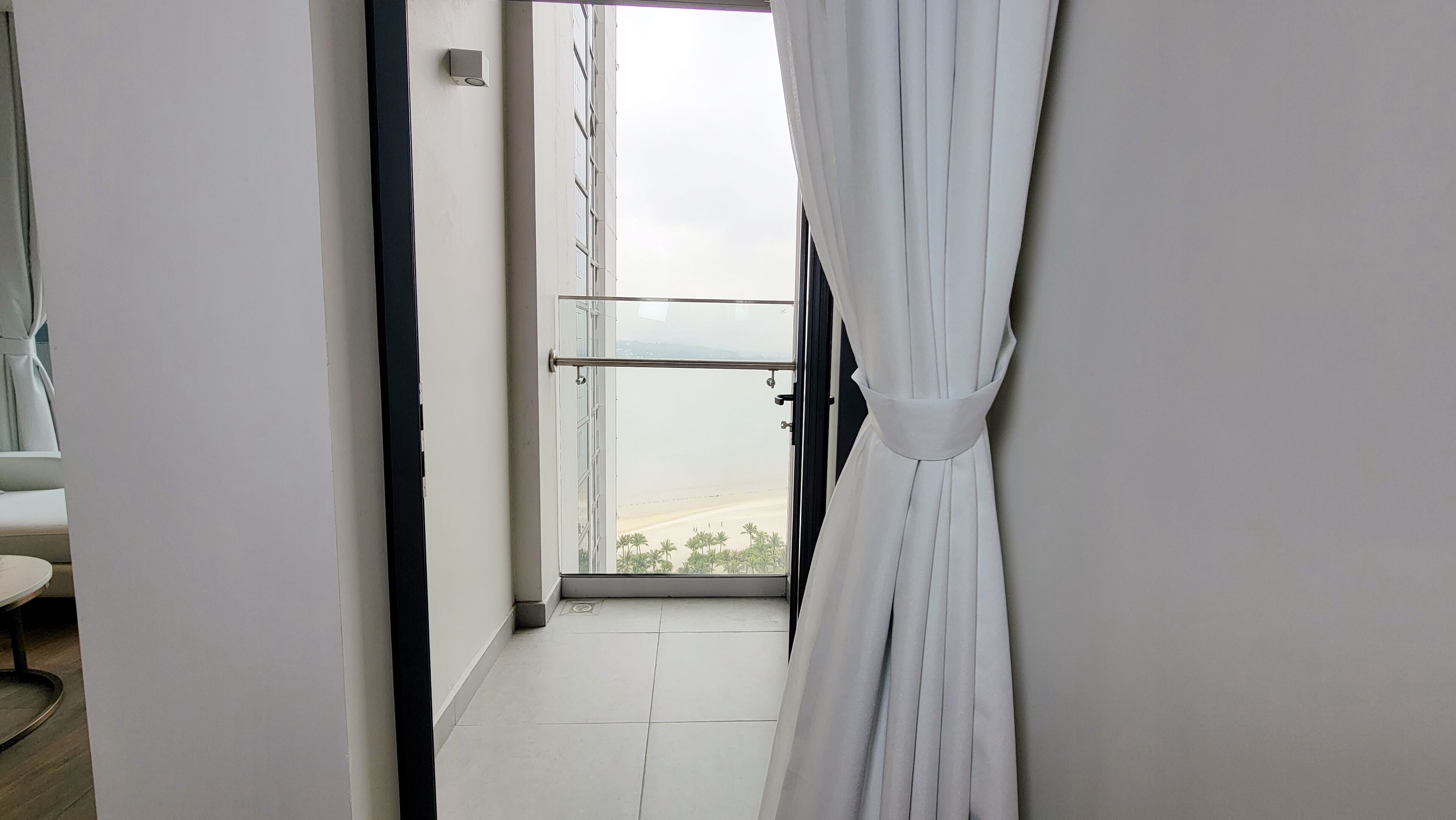 A narrow hallway with a view of a beach through a large window.
