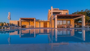 Un espace moderne aménagé au bord de la piscine, avec des chaises longues et un coin salon abrité.
