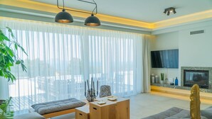 Un salon moderne doté d’une grande fenêtre, d’un téléviseur à écran plat et d’une cheminée.