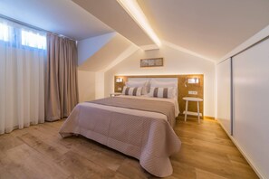 Een slaapkamer met een bed, nachtlampjes, een klein krukje en een plafondlamp.