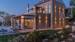 Une maison moderne à plusieurs étages, dotée d’un vaste espace extérieur comprenant une piscine et un coin salon extérieur.