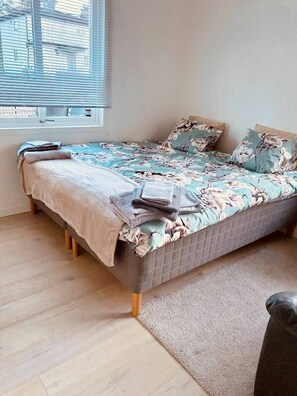 A bedroom with a bed, a window, and a view of buildings outside. - Lovely 2-bed Flat In Stockholm (Sollentuna)