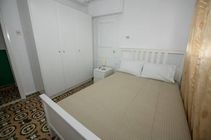 Quarto com cama, mesa de cabeceira e guarda-roupa.