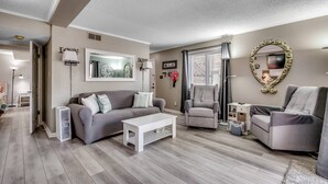 A living room with a grey sofa, a white coffee table, and a grey armchair.
