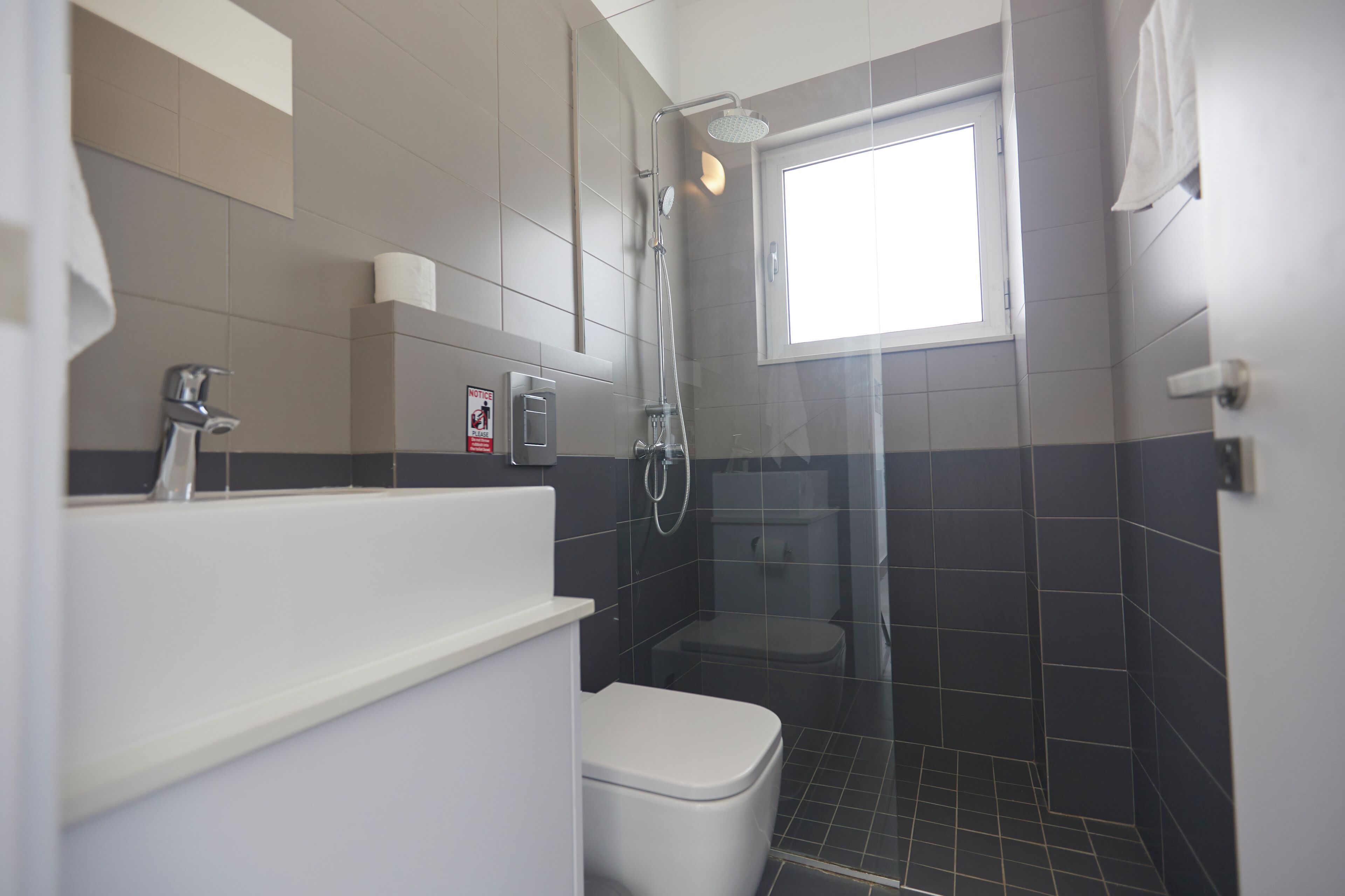 Une salle de bain moderne avec une douche, des toilettes et une fenêtre.