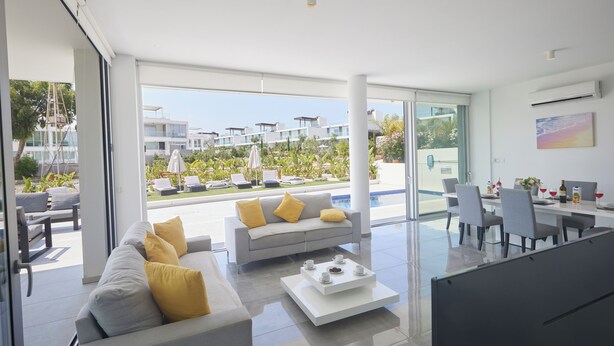 A modern living room with a sofa, coffee table, and dining area with chairs and a table.