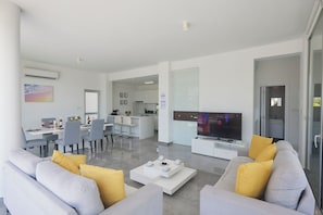 A modern living room with a sofa, coffee table, and TV. - Protaras Olivine Villa Ol01 (Paralimni)