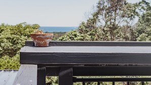A terracotta pot with a plant on a wooden railing overlooking a scenic landscape. - Victoria St. Beach House, Coffs Jetty
5 Bedroom PET Friendly Airconditioned (Coffs Harbour)