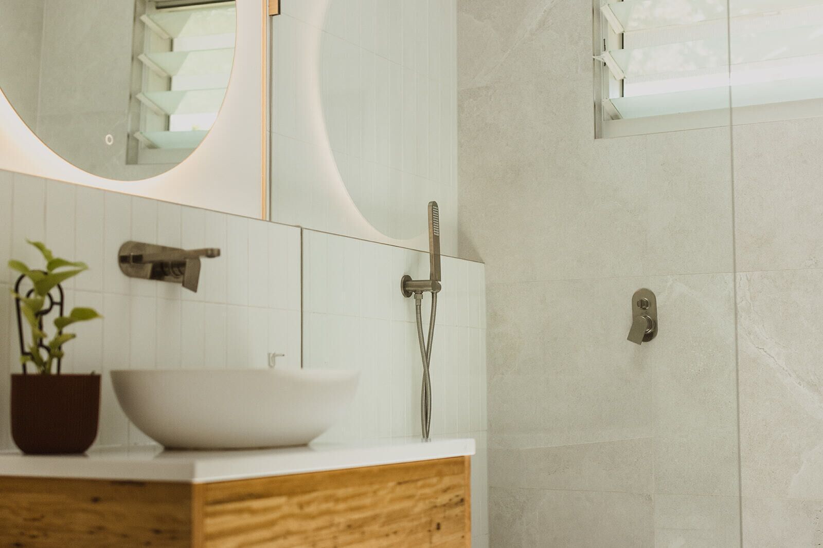 A modern bathroom with a large mirror, a white sink, and a shower.