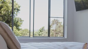 A bedroom with a bed, a window, and a view of trees. - Victoria St. Beach House, Coffs Jetty
5 Bedroom PET Friendly Airconditioned (Coffs Harbour)