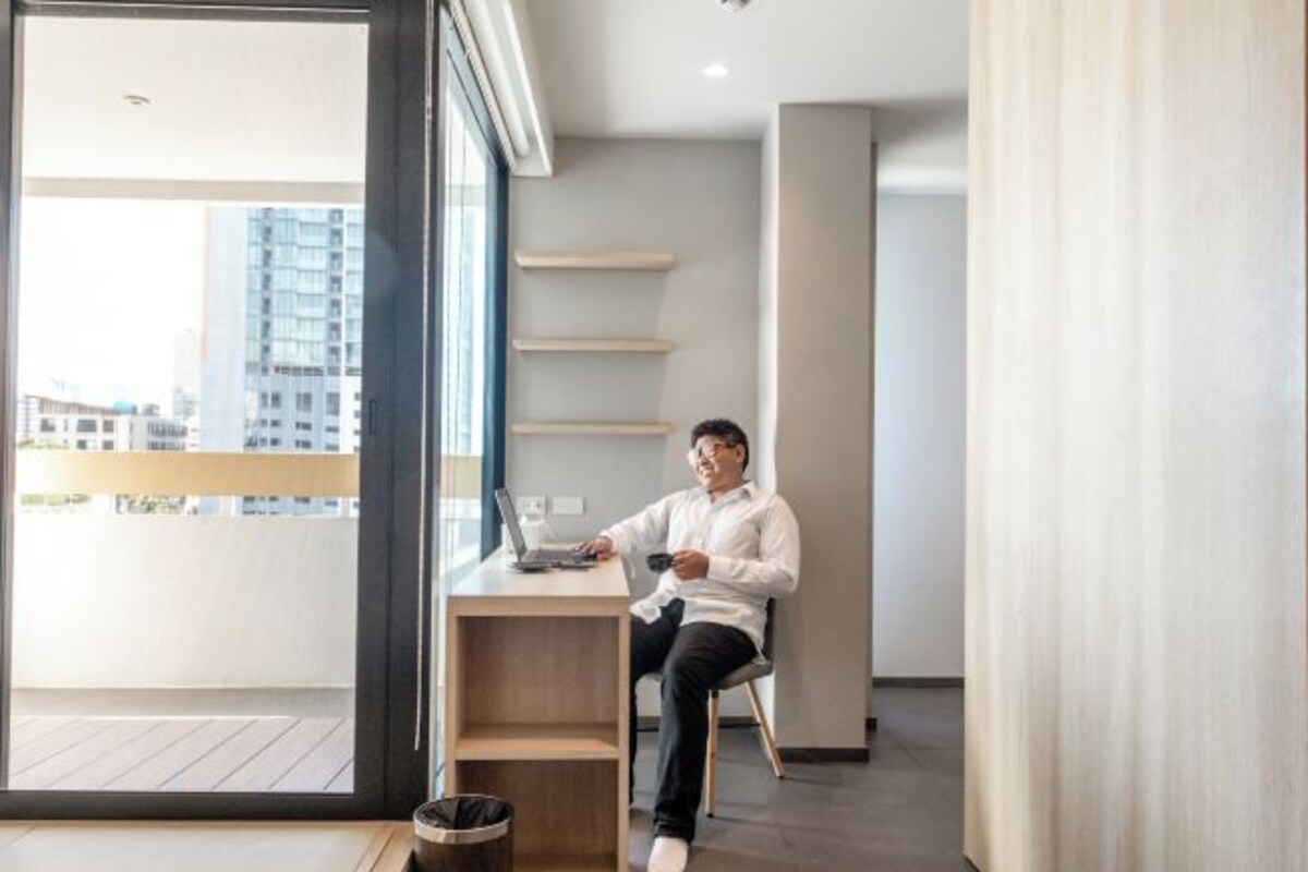 Un appartement moderne avec un balcon, un ordinateur portable sur un bureau et une poubelle.