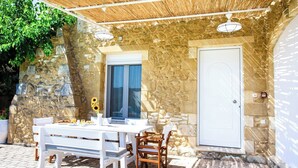 Un patio al aire libre con un muro de piedra, una mesa blanca y sillas.