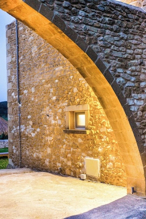 A stone building with a window under an archway, a visible electrical outlet, and a concrete ground. - Mysigt Villa - Next To Platanias, 2min From Beach (Platanias)
