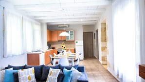 Una sala de estar moderna con un sofá, un comedor con mesa y sillas, y una cocina al fondo.