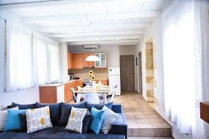 A modern living room with a sofa, a dining area with a table and chairs, and a kitchen in the background. - Mysigt Villa - Next To Platanias, 2min From Beach (Platanias)