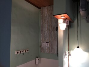 Una habitación con panel de madera en la pared, un tablero de interruptores blanco y un aplique de pared.