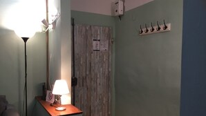 A room with a wooden door, a lamp on a table, and a wall-mounted coat rack. - Servi 39 in Firenze With 2 Bedrooms and 2 Bathrooms (Florence)