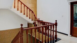 A staircase with wooden balusters and a handrail, leading to a landing with a door. - Hotel O Jr Residence Syariah (Medan)