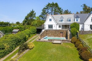 A large house with a stone exterior, a swimming pool, and a well-maintained garden. - Beautiful Home with Pool Overlooking Camel Estuary (Wadebridge)