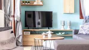 Ein modernes Wohnzimmer mit einem Flachbildfernseher, Holzböden und einem grauen Sofa.