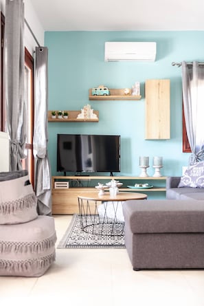 A modern living room with a flat-screen TV, wooden shelves, and a grey sofa. - Vila Vasiliki, Next To Platanias, 6min From Sea! (Platanias)