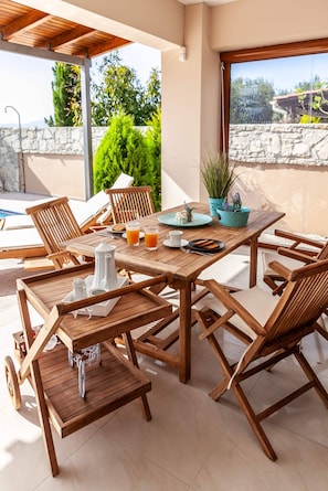 Enjoy meals and drinks in a serene outdoor setting with a comfortable table and chairs, coffee and tea amenities, and a lush view.