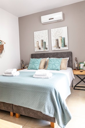 Ein Schlafzimmer mit einem Bett, einem Nachttisch, einer Wandklimaanlage und zwei Wandbildern.