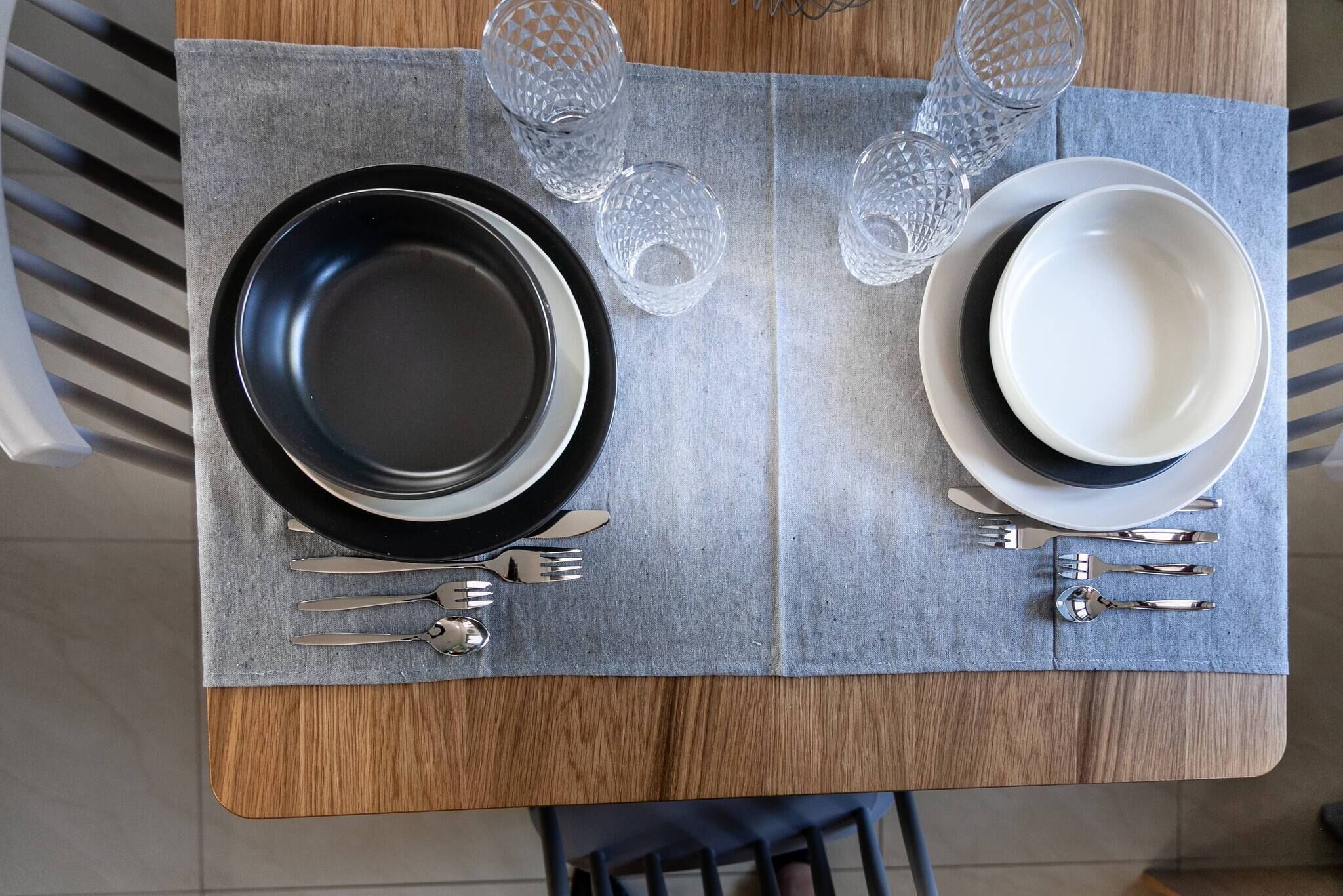 A dining table set with plates, cutlery, and glasses.