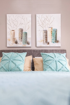Restful retreat with a neatly arranged bed and abstract artwork above.