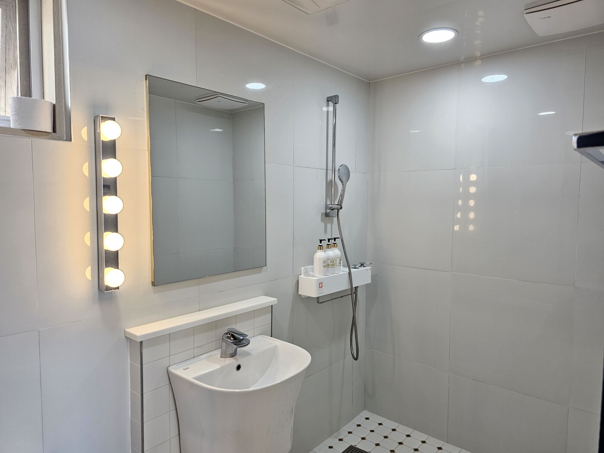 A bathroom with a sink, mirror, and shower.