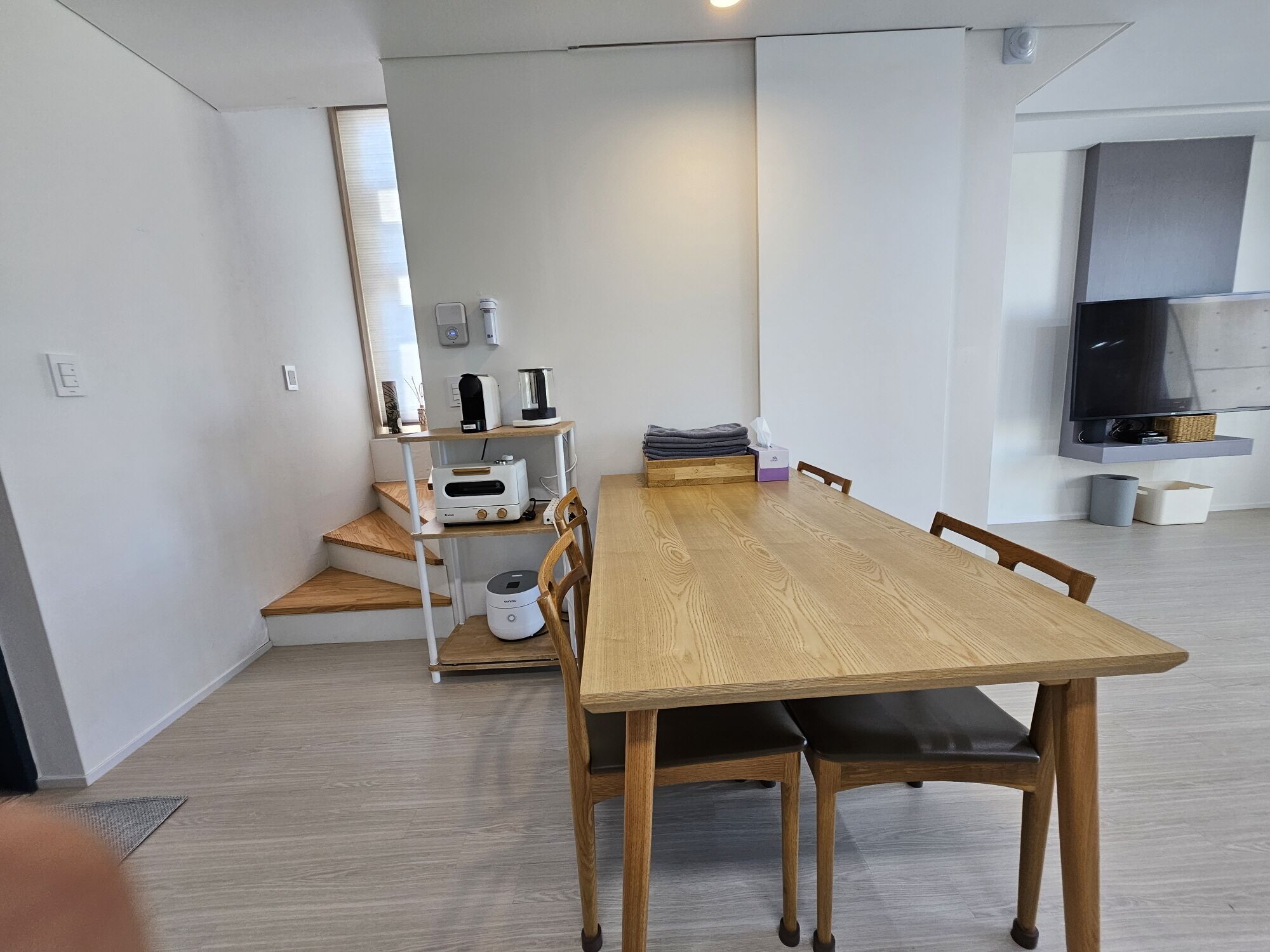 A modern kitchen with a wooden dining table, chairs, and a built-in oven.